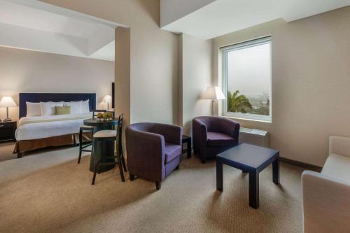 a hotel room with a bed and a table and chairs at La Quinta by Wyndham Poza Rica in Poza Rica de Hidalgo