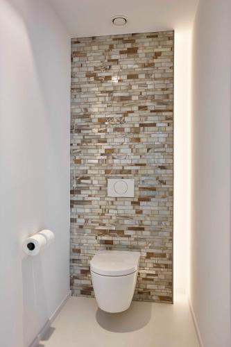 a white toilet in a bathroom with a brick wall at Parkhotel Izegem in Izegem