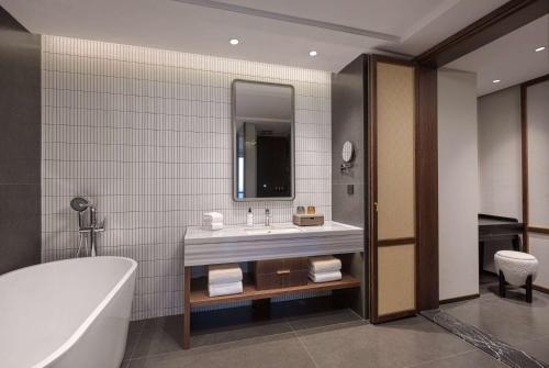 a bathroom with a tub and a sink and a mirror at Days Hotel by Wyndham Changsha Yuhua West in Changsha
