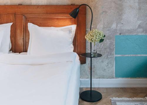 a bedroom with a bed with a lamp and a vase of flowers at Story Hotel Riddargatan, part of JdV by Hyatt in Stockholm