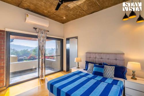 a bedroom with a bed and a large window at StayVista at LettGo with Garden, BBQ & Terrace in Mohali