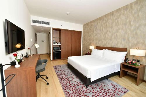 a bedroom with a bed and a desk and a television at Comfort Hotel Riyadh Olaya in Riyadh