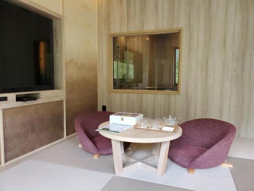 a room with two purple chairs and a table and a tv at Kamikochi Lemeiesta Hotel in Matsumoto