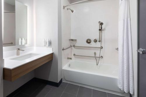 a white bathroom with a tub and a sink at Microtel Inn & Suites by Wyndham Olive Branch in Olive Branch