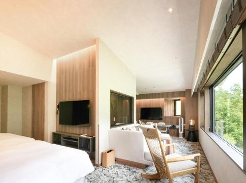 a bedroom with a bed and a living room at Kamikochi Lemeiesta Hotel in Matsumoto