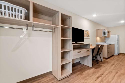a room with a desk with a computer and a tv at WoodSpring Suites Pensacola West in Pensacola