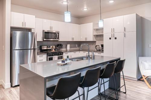 a kitchen with white cabinets and a large island with black chairs at Expansive views - 1BD 1BA Hot Tub, Pool, Convention Centre in Salt Lake City
