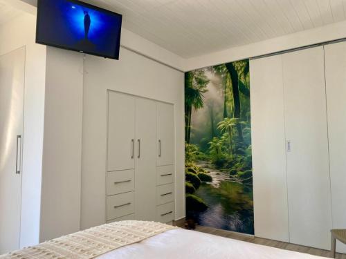 a bedroom with a painting on the wall at Anura - Luxurious Stay, 100m leap to the Beach! in Jeffreys Bay