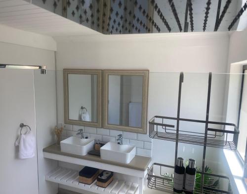 a bathroom with two sinks and two mirrors at Anura - Luxurious Stay, 100m leap to the Beach! in Jeffreys Bay