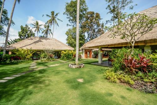 a resort yard with a thatch roof at The Hidden Paradise Ubud - CHSE Certified in Ubud