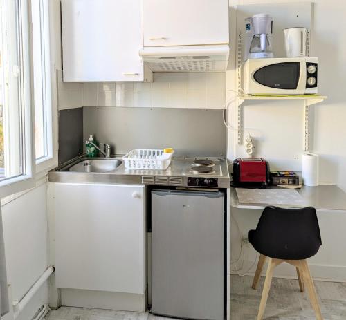 une petite cuisine avec un évier et un micro-ondes dans l'établissement La Villa Oscar en plein cœur de ville, à Dax