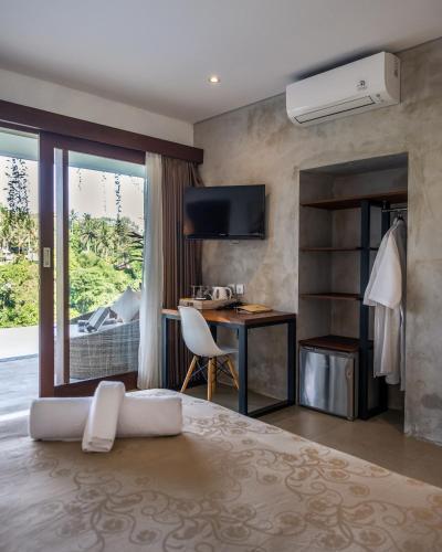 a hotel room with a bed and a desk and a window at The Hidden Paradise Ubud - CHSE Certified in Ubud