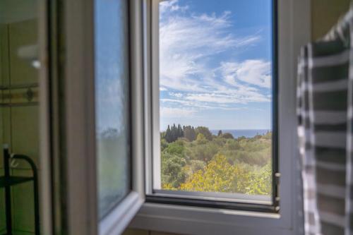 a window with a view of trees and clouds at Vista Verde Studios & Apartments in Svoronata