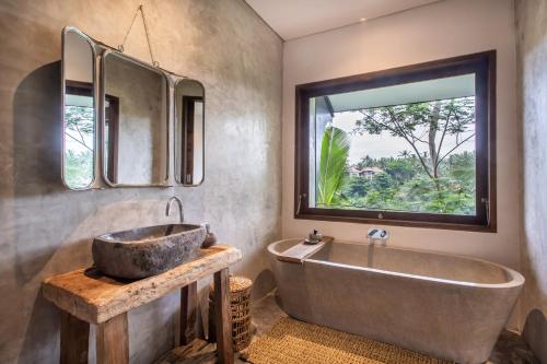 a bathroom with a large tub and a window at The Hidden Paradise Ubud - CHSE Certified in Ubud