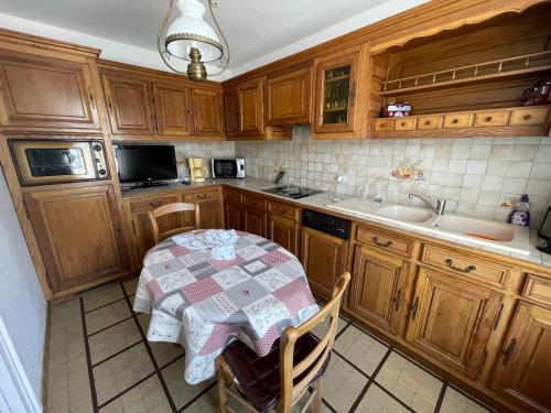 - une cuisine avec des placards en bois, une table et un évier dans l'établissement Maison 3 chambres pour 6 pers, à Sartilly