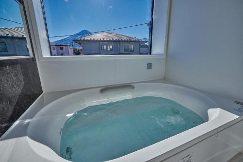 a bath tub filled with blue water next to a window at MIYA HOUSE Funatsu B in Fujikawaguchiko