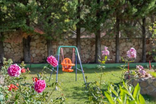 an orange swing in a yard with pink flowers at Vista Verde Studios & Apartments in Svoronata