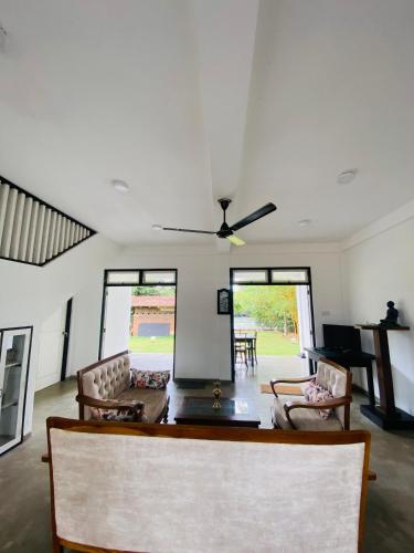 a living room with a ceiling fan and a table and chairs at Silver Lake Villa & Boat Safari in Balapitiya