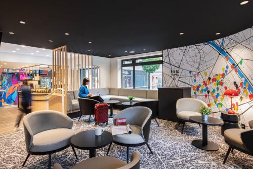 a woman sitting in a waiting room with chairs and tables at ibis Paris Avenue d'Italie 13ème in Paris