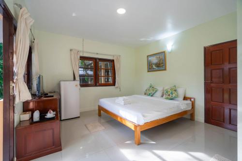 a bedroom with a bed and a refrigerator in it at Puprai Tarnnarm Resort in Thong Pha Phum