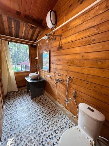 a wooden bathroom with a toilet and a sink at Mountain Breeze Wooden Cottages in Agonda