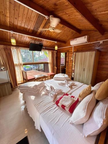 a large white bed in a room with wooden ceilings at Mountain Breeze Wooden Cottages in Agonda