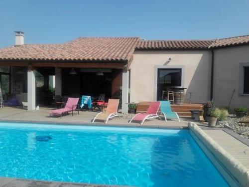 a swimming pool with chairs and a house at Beautiful architectural villa 10 pool beds in Laure-Minervois