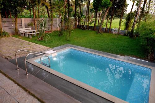 a large swimming pool in a backyard with a picnic table at Serene Retreat in Cochin