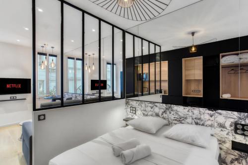 Cette chambre comprend un lit blanc et de grandes fenêtres. dans l'établissement F2 rue St honoré D ,Hypercentre à 2 minutes du Palais des congrès, à Cannes