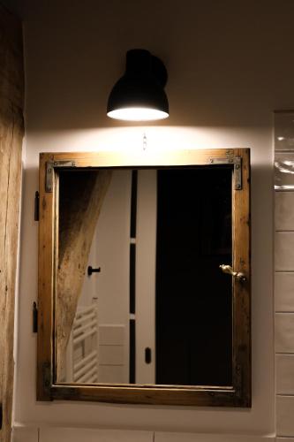 a mirror with a wooden frame and a light at Ugron Castle Fiatfalva in Cristuru Secuiesc