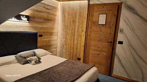 a bedroom with a bed and a wooden wall at Hotel Valle Pesio Ristorante in Chiusa di Pesio