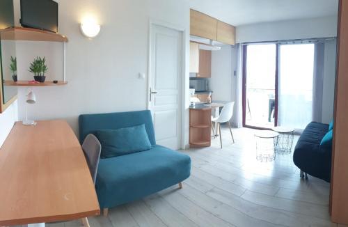 un salon avec un canapé bleu et une table dans l'établissement Appartement La Rochelle, à La Rochelle