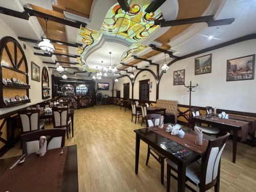 a restaurant with tables and chairs and a stained glass ceiling at Hotel&Restaurant SENATOR in Truskavets