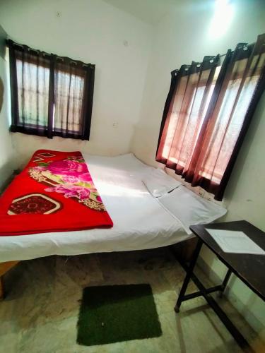 a small bedroom with a bed with a red blanket at Shivay Guest house in Jasidih