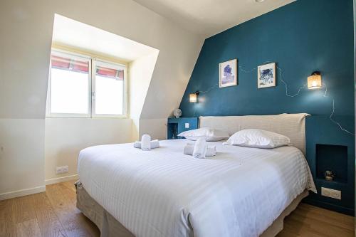 - une chambre avec un grand lit blanc et un mur bleu dans l'établissement Very nice apartment-Roof Top, à Blonville-sur-Mer