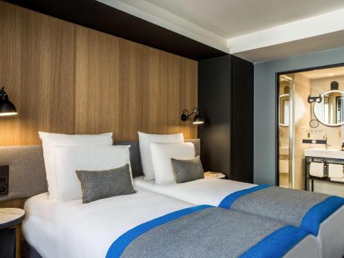 a hotel room with a large white bed with two pillows at Mercure Paris 17 Batignolles in Paris