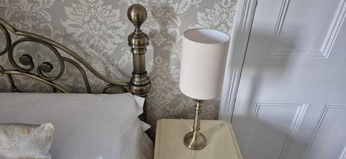 a lamp on a night stand next to a bed at Denehurst Guest House - Adults Only in Windermere