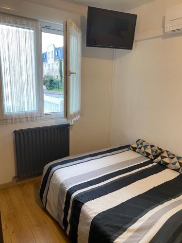 a bedroom with a bed with a television on the wall at Nancy, Magnifique studio totalement climatisé, meublé, salle de bains et wc séparés, parking privé, cuisine équipée, WIFI in Malzéville