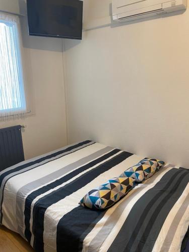 a bedroom with a bed with two pillows on it at Nancy, Magnifique studio totalement climatisé, meublé, salle de bains et wc séparés, parking privé, cuisine équipée, WIFI in Malzéville