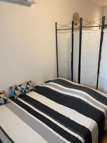 a bed with a black and white striped blanket at Nancy, Magnifique studio totalement climatisé, meublé, salle de bains et wc séparés, parking privé, cuisine équipée, WIFI in Malzéville