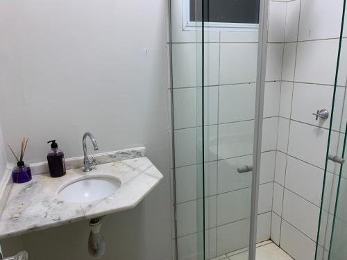 a bathroom with a sink and a glass shower at Casa de temporada Uberaba MG in Uberaba