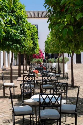 a row of tables and chairs in a courtyard with trees at Hospedium hotel Cortijo Torre De La Reina in Torre de la Reina