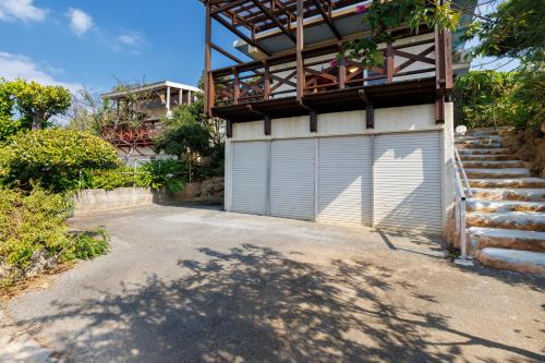 a garage door on a house with a balcony at オーシャンビューの絶景UnclesHouse海の宿は美ら海水族館近く1棟貸 in Motobu