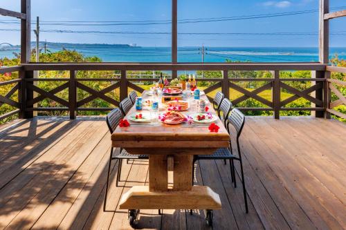 a wooden table with food on it on a deck at オーシャンビューの絶景UnclesHouse海の宿は美ら海水族館近く1棟貸 in Motobu