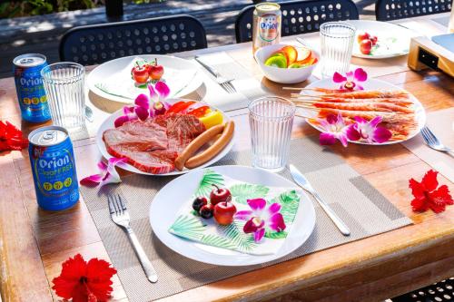 a wooden table with plates of food on it at オーシャンビューの絶景UnclesHouse海の宿は美ら海水族館近く1棟貸 in Motobu