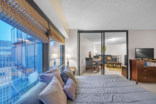a bedroom with a bed and a balcony with a view at Chic DT Honolulu Executive Condo condo in Honolulu
