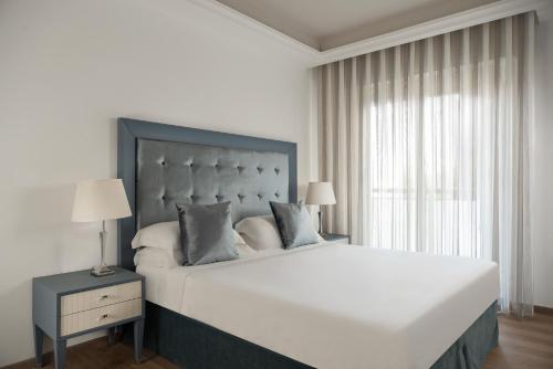 a white bedroom with a large bed and a window at Grand Hotel Gallia in Milano Marittima