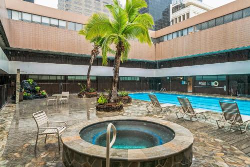 a pool with chairs and palm trees in a courtyard at Chic DT Honolulu Executive Condo condo in Honolulu
