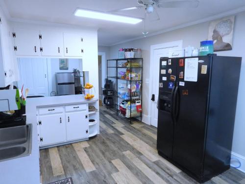 a kitchen with a black refrigerator and white cabinets at The Blue Victorian Waterview Home in Hampton