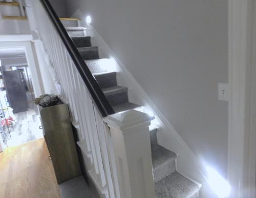 a stairway with white walls and a white stair case at The Blue Victorian Waterview Home in Hampton